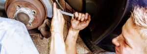 man checking brakes on a car